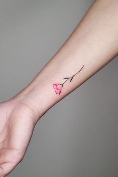 a small pink flower tattoo on the wrist