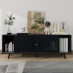 a black sideboard with books and vases on it in front of a white wall