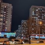 cars are parked on the street in front of tall buildings at night with lights shining