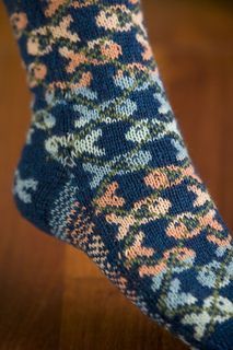 a person's feet wearing socks with flowers and leaves on them, sitting on a wooden floor