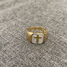 a gold and white ring with a cross on the front, sitting on a gray surface