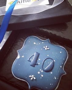 a blue birthday cake with the number forty on it's side, sitting in front of a black box