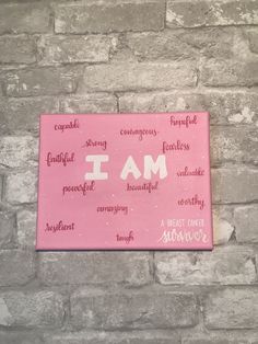 a pink sign that says i am on the side of a brick wall