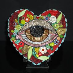 a heart shaped object with an eye on it's face and flowers around the eyes