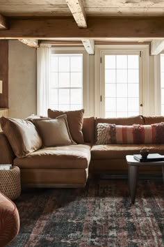 a living room filled with lots of furniture next to two windows and a rug on the floor