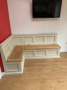 a tv mounted to the side of a wall next to a wooden bench in a room