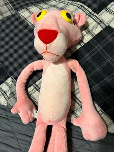 a pink stuffed animal sitting on top of a black and white checkered bedspread