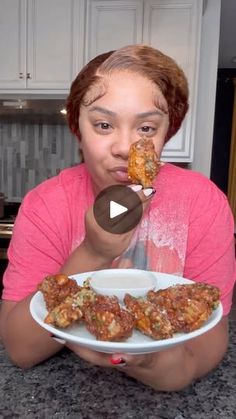 a woman eating food from a white plate on top of a kitchen counter next to an oven