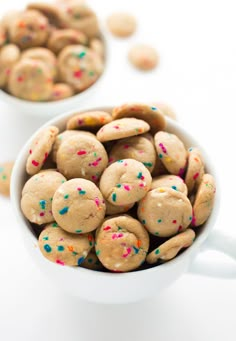 two bowls filled with cookies and sprinkles on top of a white table