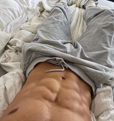 a shirtless man laying on top of a bed