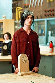 a man standing next to a wooden clock on top of a table in a room