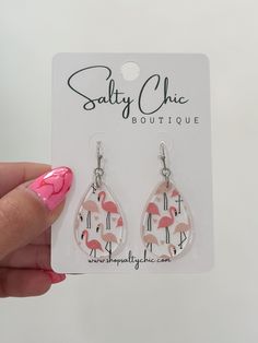 a pair of earrings with pink flamingos printed on the front and back of them