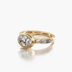 a yellow gold ring with an oval diamond and baguettes