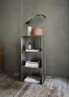 a metal shelf with books and plants on it in a room that has wood floors