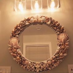 there is a mirror with shells on it and lights above the mirror in the bathroom