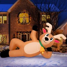 a large inflatable reindeer laying on its back next to a house with christmas lights