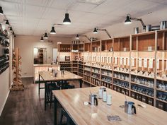 an empty restaurant with wooden tables and shelves full of bottles on the wall, along with hanging lights