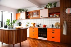 an orange and white kitchen with wood flooring, potted plants on the counter