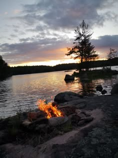 a campfire on the shore of a lake at sunset