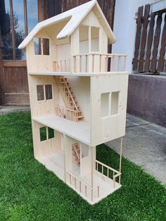 a doll house made out of wood sitting on the grass