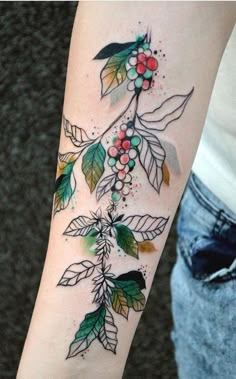 a woman's arm with leaves and berries on it