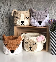 three crocheted baskets with animals on them sitting next to a plant in a vase