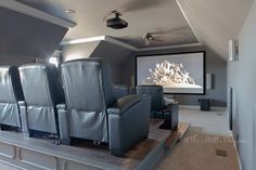 a home theater with leather chairs and a projector screen in the middle of it