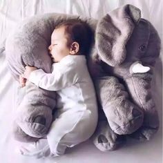 a baby is sleeping next to an elephant pillow