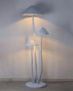 three white mushrooms are on the floor next to a lamp