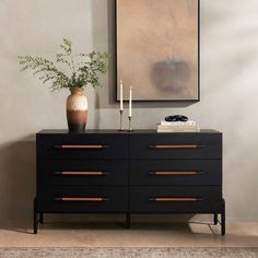 a black dresser with two candles and a vase on top