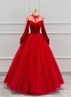 Imbued with regal elegance, this prom dress is a treasure trove of design details that create a narrative of sophistication. The alluring high neckline with lace overlay sets a tone of aristocratic grace, inviting onlookers to a dance of the eyes towards the sheer, full-length sleeves that whisper of a bygone era's charm. The heart-shaped lining beneath the translucent fabric provides a tasteful allure, while the expansive skirt, adorned with glimmering sequins scattered across the tulle, offers a spectacular display of opulence. This dress does more than drape; it hugs the form in a loving embrace, enhancing the silhouette and empowering the wearer with an air of undeniable majesty. Perfect for the prom-goer who desires to embody a story of elegance, this gown promises to weave an enchant Prom Dress Long Sleeve, Floor Length Prom Dress, Velvet Prom Dress, Prom Dress Long, Tulle Sleeves, Floor Length Prom Dresses, Red Ball, Long Sleeve Prom, Beautiful Prom Dresses