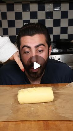 a man making bread on top of a wooden counter next to a knife and spatula