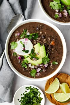 three bowls of black bean soup with avocado and cilantro