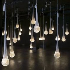 a group of lights hanging from the ceiling in a room with black walls and flooring