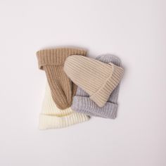 three different colored knitted mittens laying on top of each other