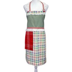 a white mannequin wearing an apron with red and green plaid trimmings