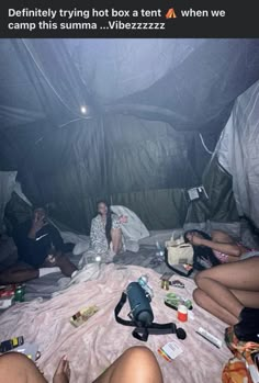 four people sitting on a bed in a tent with food and drinks scattered around them