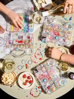 several people are sitting at a table covered with beads and other things to make crafts