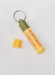 an orange and yellow keychain sitting next to a tube of lip bale