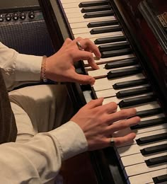 two hands are playing the piano while another person is wearing a watch on their wrist