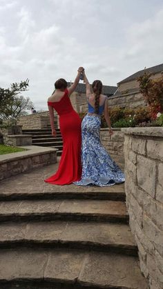 two women in dresses are standing on some steps and one is holding the other's hand