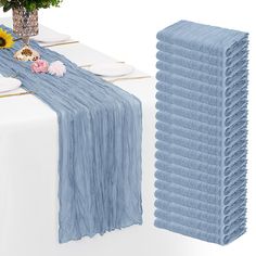 a blue table runner with flowers and plates on it next to a white table cloth