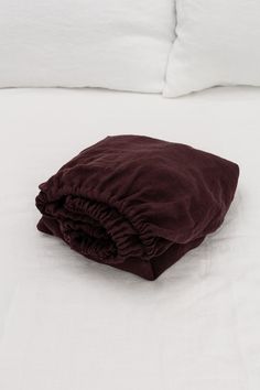 an unmade bed with white sheets and brown blankets on it's headboard