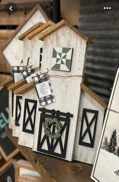 several birdhouses are hanging on a wooden shelf next to pictures and frames in the shape of houses