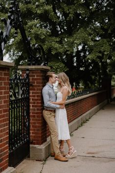 a man and woman standing next to each other near a fence