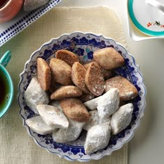 a bowl filled with marshmallows on top of a table next to cups and saucers