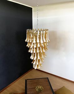 a chandelier hanging from the ceiling in a room with black walls and wooden flooring