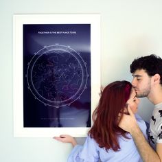 a man and woman standing next to each other in front of a wall with a poster on it