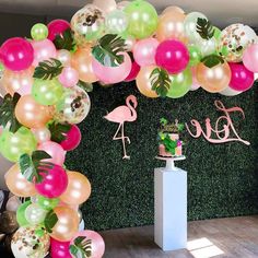 the balloon arch is decorated with flamingos and tropical leaves