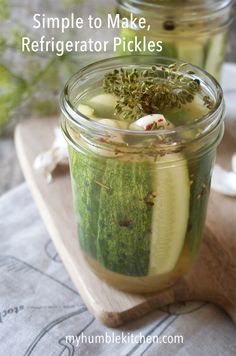 two jars filled with pickles on top of a wooden board